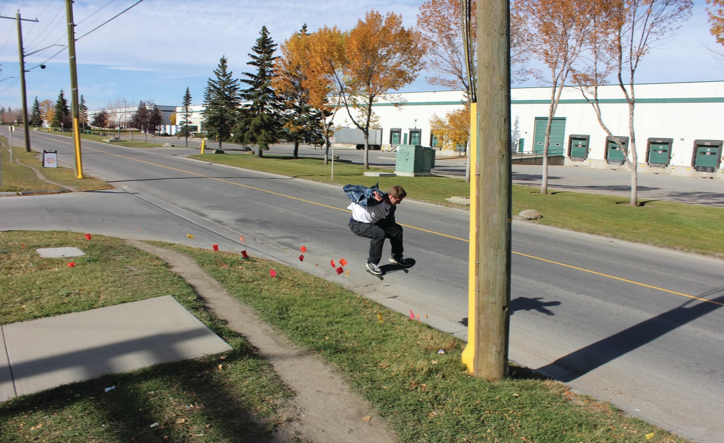 Skater ollieing beside an industrial road
